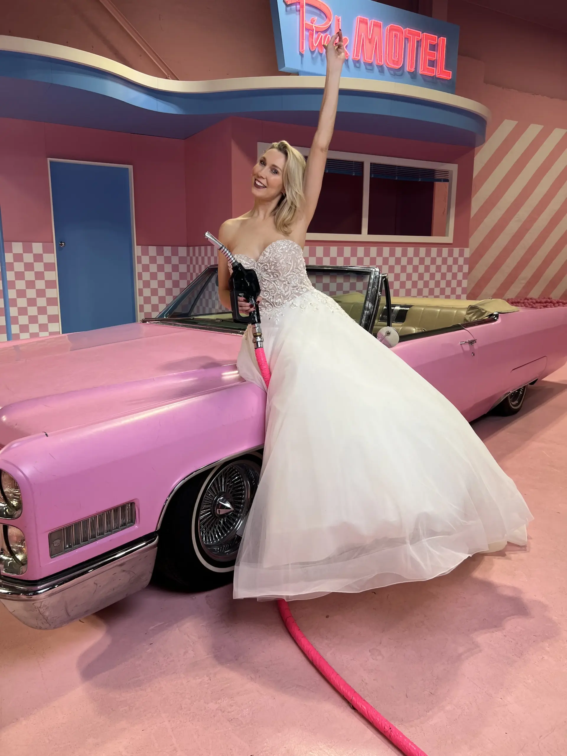 Model im Brautkleid von Cinderella Brautmode neben einem rosa Oldtimer im Candy Museum